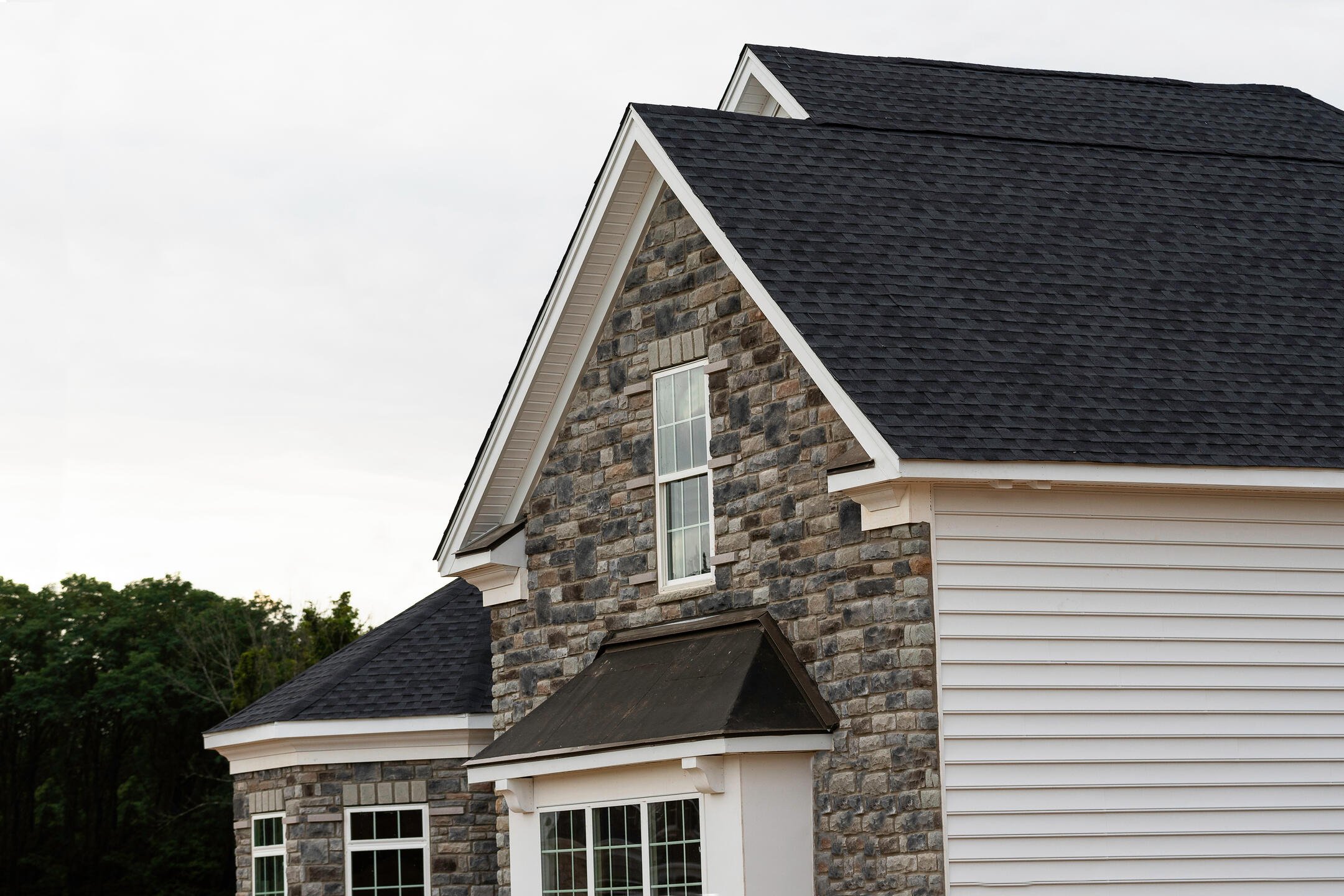 black shingles-stone and white sided house with black shingle roof