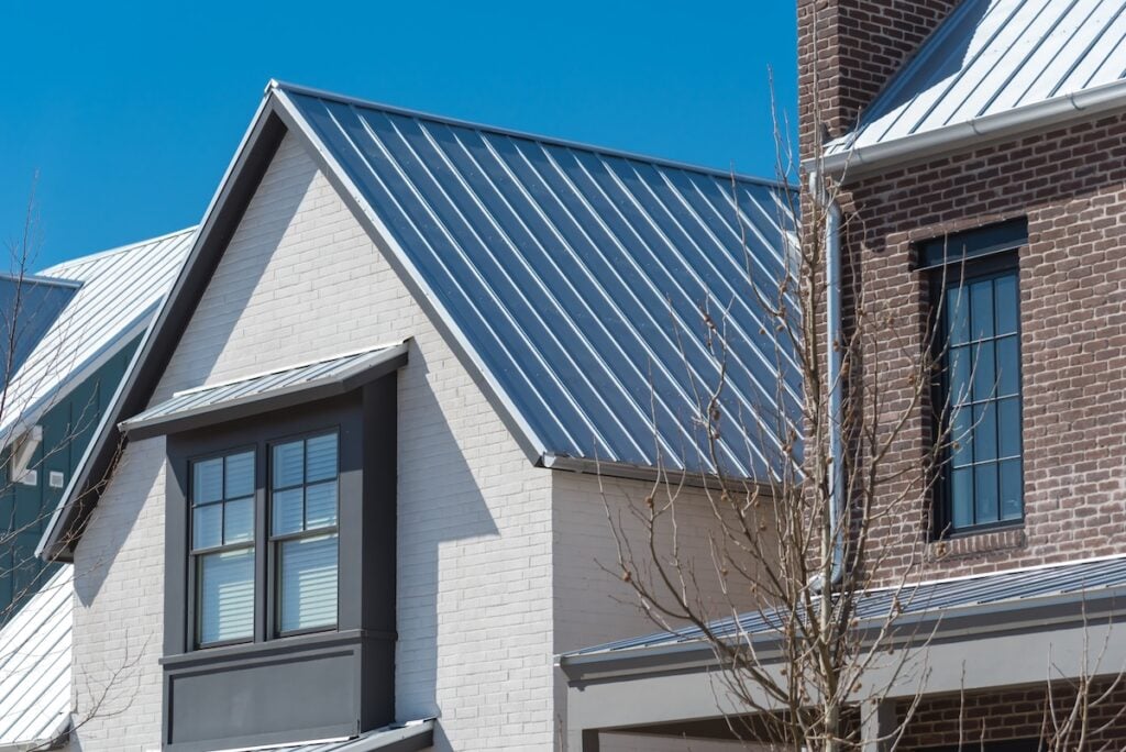 Close-up second floor of brand new house with metal roof and covered gutter near Oklahoma City, US. Modern two story townhouse with bay windows and thin brick siding sunny winter day blue sky v can you paint a metal roof