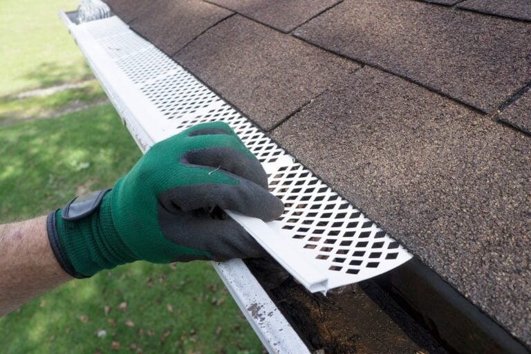 Contractor adjusting plastic gutter guards to get them to fit.