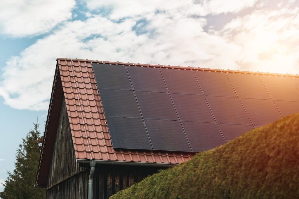 Modern black cells solar panels on the roof of private house. Photovoltaic dotation from European parliament government concept. Renewable energy for the home concept. Sustainable living future.