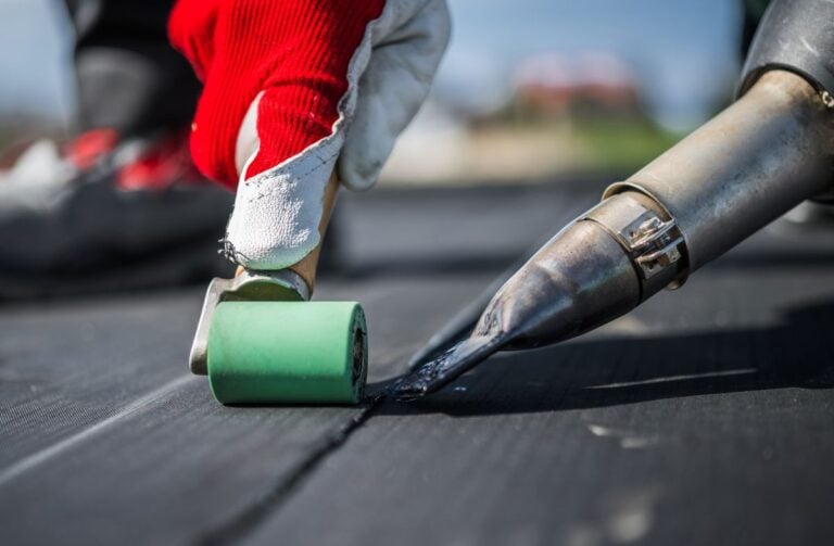 epdm roof sealant closeup worker using roller and hot air blower repair